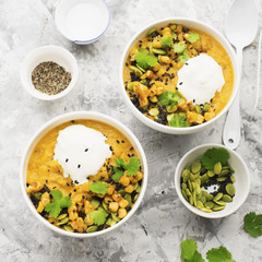 Cream soup from baked juicy young corn with pumpkin seeds, black sesame, cilantro in a bowl with a gray background with sour cream and cutlery. Top View.