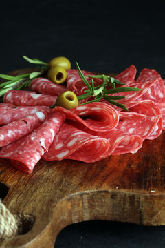 thinly sliced salami on a wooden cuttingboard