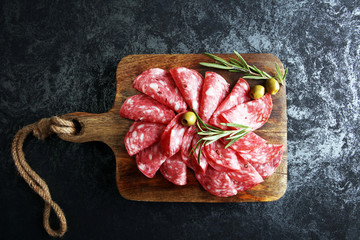 thinly sliced salami on a wooden cuttingboard - obrazy, fototapety, plakaty