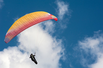 Paraglider flying in the blue sky against the background of clouds. Paragliding in the sky on a sunny day.