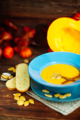 Pumpkin and carrot soup with cream and parsley on dark wooden background Top view