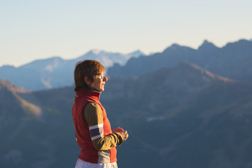 One person looking at the majestic view of glowing mountain peaks at sunset high up on the Alps. Rear view, toned and filtered image, focus in the background.