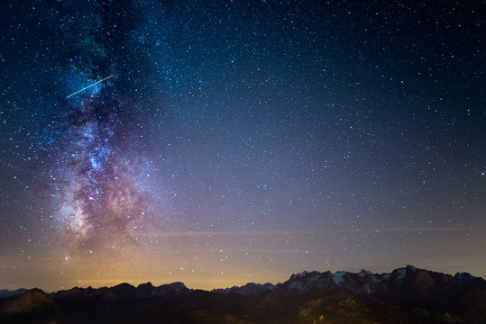 The colorful glowing Milky Way and the starry sky over the French Alps and the majestic Massif des Ecrins.