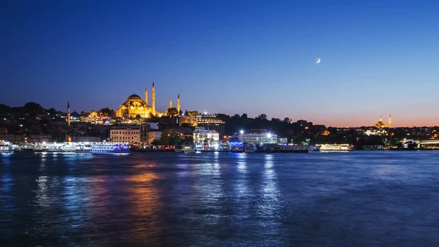 Zoom out Timelapse view of Istanbul cityscape with Suleymaniye mosque with tourist ships floating at Bosphorus at night