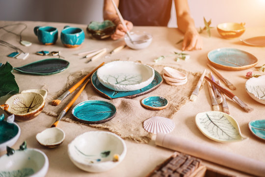 Potter molds a cup of clay. The young potter decorates a cup of clay