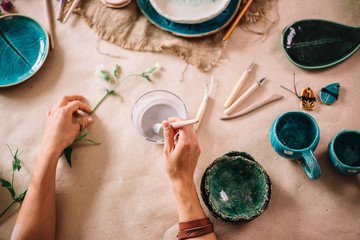 Potter molds a cup of clay. The young potter decorates a cup of clay