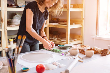 Ceramist using plants to print on a clay