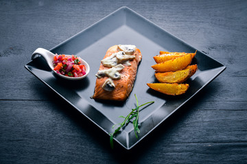 Baked salmon with mushroom sauce and potatoes. On a wooden background. Top view. Free space.
