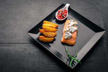 Baked salmon with mushroom sauce and potatoes. On a wooden background. Top view. Free space.