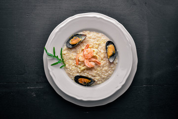 Risotto with seafood, shrimp, mussels and squids and cheese. On a wooden background. Top view. Free space.