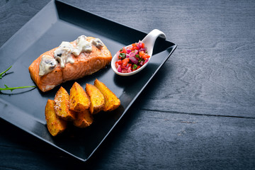 Baked salmon with mushroom sauce and potatoes. On a wooden background. Top view. Free space.