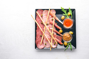 Meat slices on a plate with ketchup and mustard. Sausage and bacon. On a wooden background. Top view. Free space.
