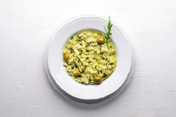 Risotto with spinach, cheese and olives. On a wooden background. Top view. Free space.