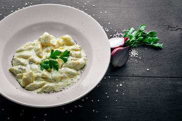 Dumpling from potatoes under cheese sauce. On a wooden background. Top view. Free space.