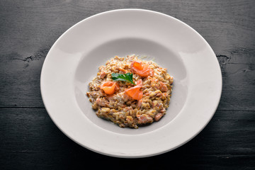 Risotto with salmon and cream sauce. On a wooden background. Top view. Free space.