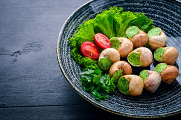 French and Italian cuisine. Baked snails. On a wooden background. Top view. Free space.