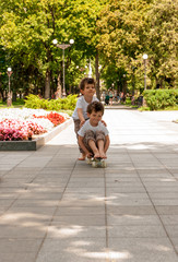 Twin boys roll each other on a skateboard outdoors in the park © Germanova Antonina