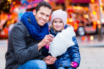 Father on Christmas market buying sweets for child daughter