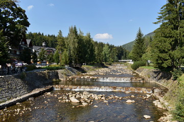 Fototapeta na wymiar River in a Small Town, Mountains and Blue Sky
