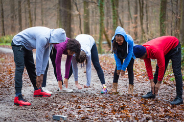 Young group of five people practicing bending exercise for warming up the upper-body outdoors