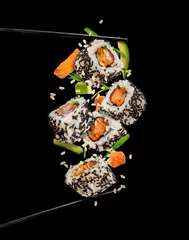 Deurstickers Sushi stukken geplaatst tussen eetstokjes op zwarte achtergrond © Jag_cz