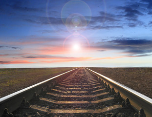 landscape with rails going away into the sunset and evening sun