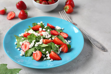 Plate with strawberry spinach salad on table