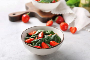 Bowl with strawberry spinach salad on table