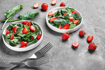 Plates with strawberry spinach salad on table