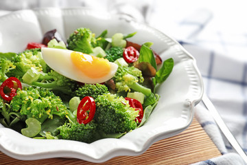 Dish with broccoli salad on wooden board