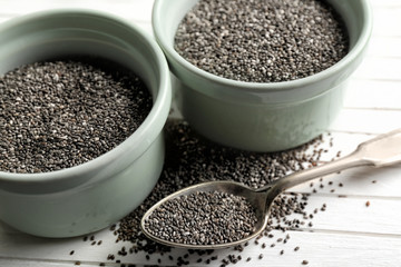 Chia seeds in bowls and spoon on table