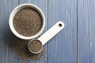 Chia seeds in scoop and bowl on table