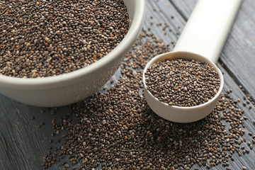 Chia seeds in scoop and bowl on table, closeup