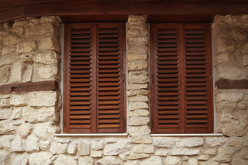 Fototapeta na wymiar Stone wall with two shuttered windows