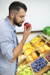 Obraz premium Young man with peach at market