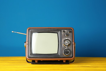 Vintage television on wooden table near color wall