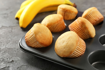 Fresh banana muffins in baking tray on table, closeup