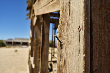 Nail in wood close up. Ruined building in the desert.