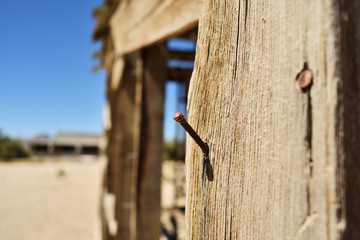 Nail in wood close up. Ruined building in the desert.
