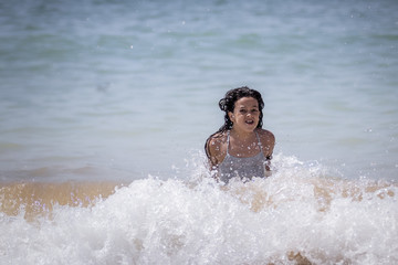 Niña morena bañándose en el mar y jugando con las olas.