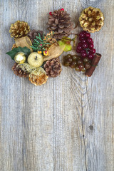 Christmas decorations with golden pine cones, apples and balls over a rustic wooden board.