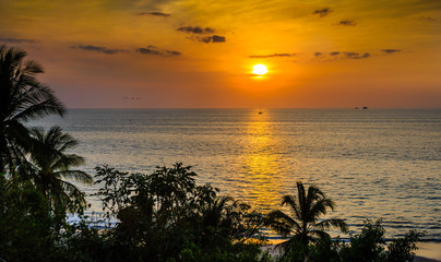 Fototapeta na wymiar Tropical ocean sunset with sailboat silhouette