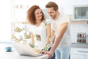 Happy young couple with laptop in kitchen