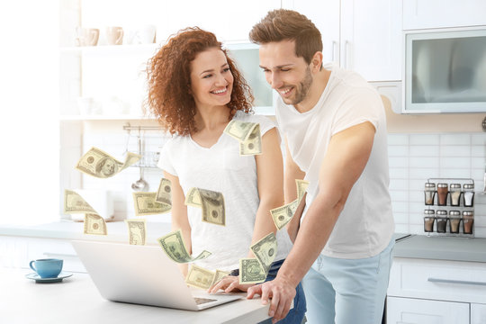 Happy Young Couple With Laptop In Kitchen