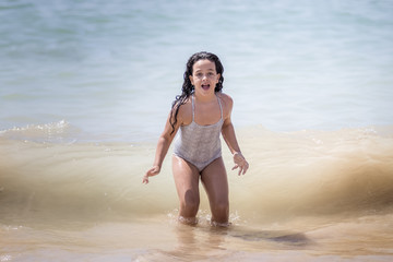 Niña morena bañándose en el mar y jugando con las olas.