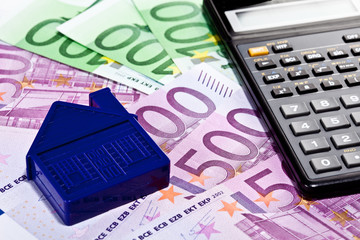 Small house model, euro banknotes and calculator