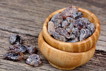 Brown candy crystals in a bamboo bowl on table