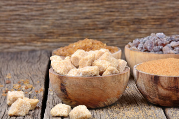 Different kinds of sugar in a bowls on wooden background