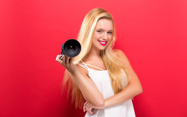 Young woman comparing professional camera on a solid background