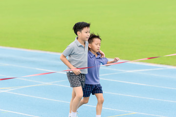 Young Asian boy running on blue track in the stadium